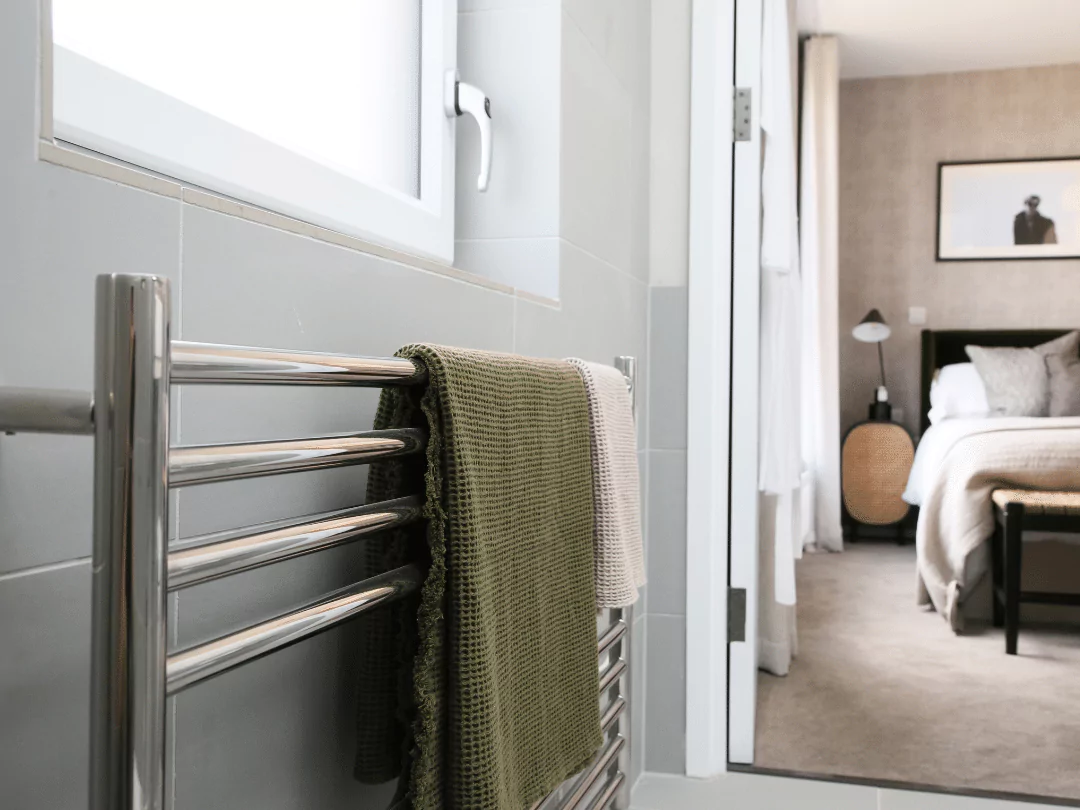 Close up image displaying soft touch towels hanging on a heated towel warmer in the en-suite.