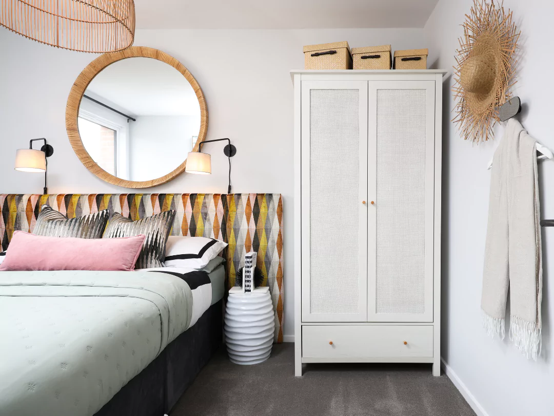A glimpse into the double guest bedroom featuring a funky headboard, a rattan white wardrobe and stylish extras.