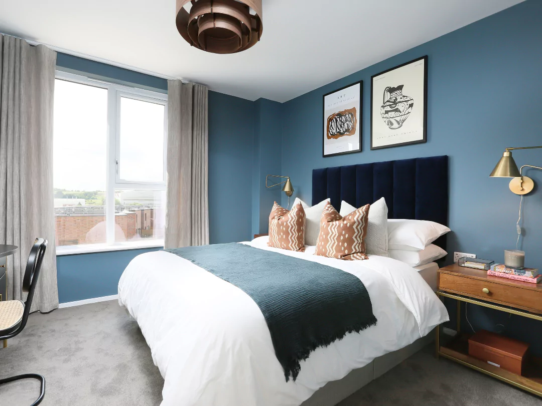 Deep blue decor and wood accents complement the apartment double guest bedroom.