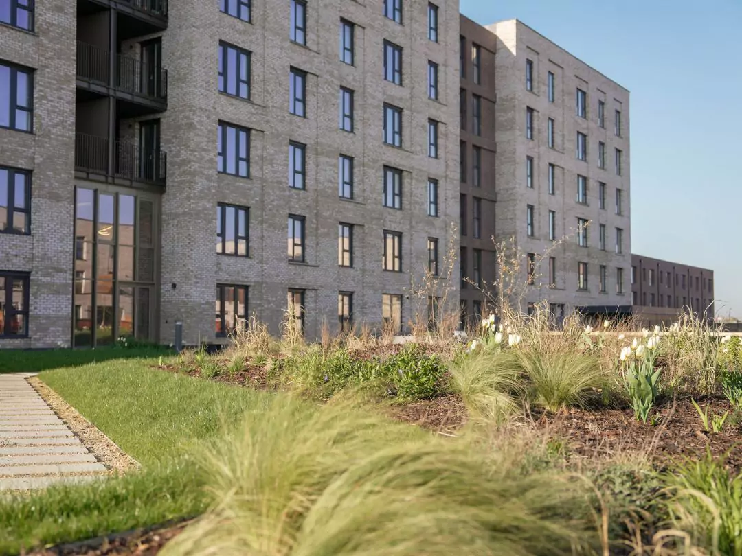 Modern apartment building at Brabazon, Bristol with green landscaping under blue sky.