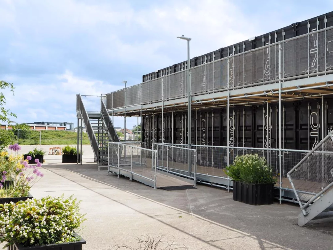  A black commercial office container building with metal stairs and a railing on the exterior.