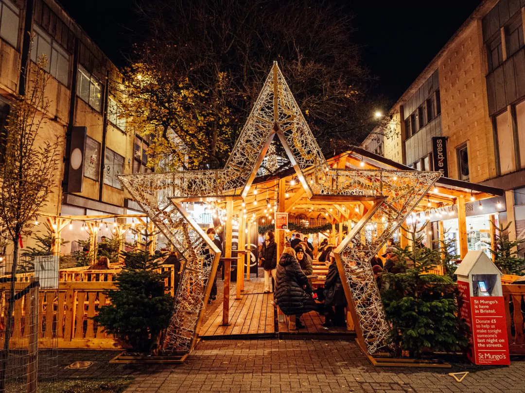 People enjoying mulled wine in a traditional pop-up bar at Bristol Christmas market.