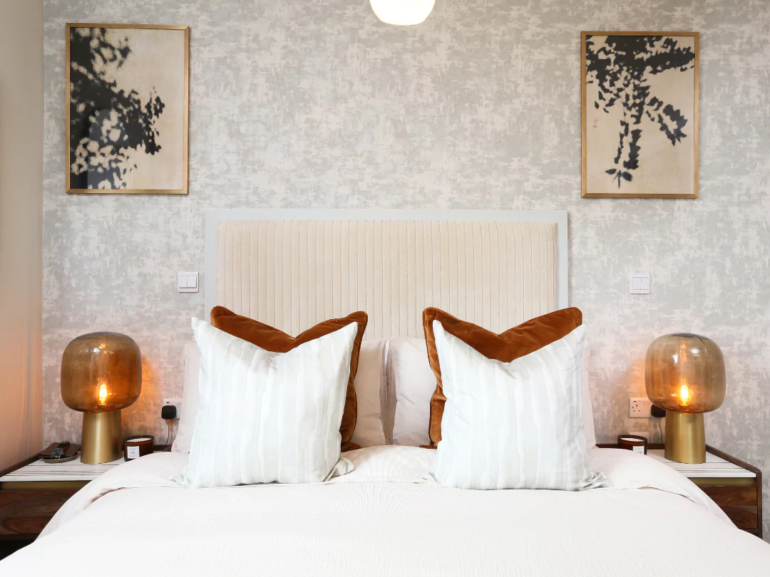 Burnt orange decor and matching bedside tables compliment this apartment primary bedroom.